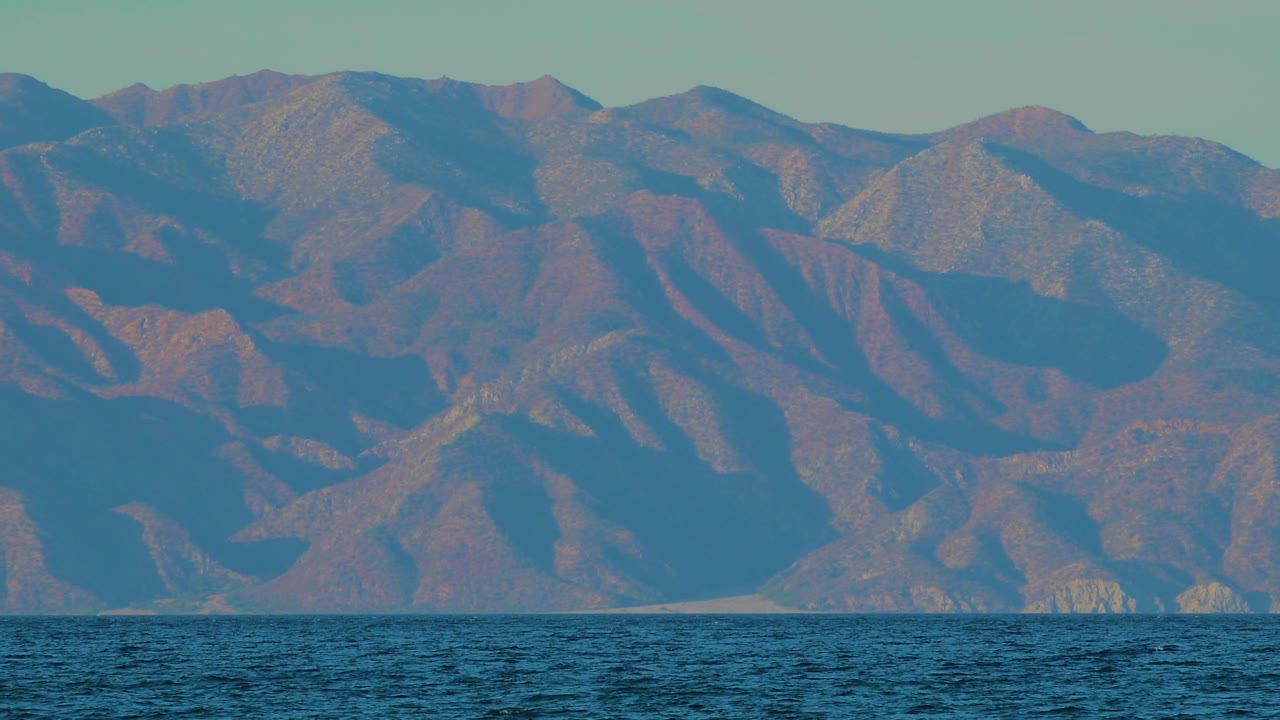 Mountain slope details above rippled ocean.