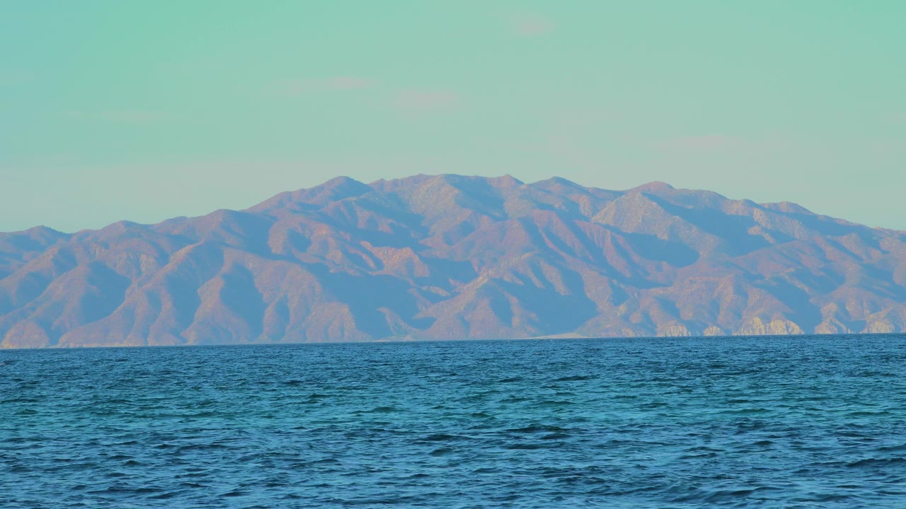 Choppy blue sea below distant mountains and pale sky.