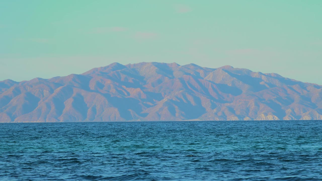 At two seconds, the blue water appears slightly darker in the foreground, with hazy mountains and a clear pale sky in El Sargento La Ventana, Mexico, and no visible people.