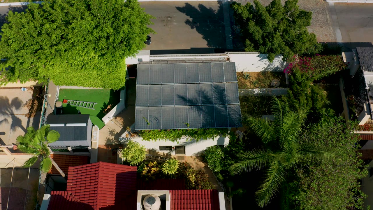 Overhead Los Cabos residential view with a gray roof, red roof tiles, palms, garden paths, and no visible people.