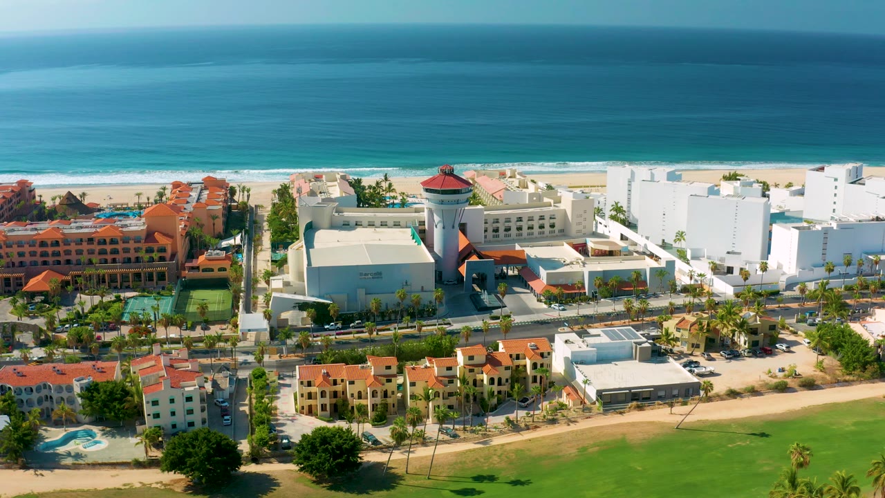 Closer aerial view of resort buildings, beach, and calm ocean.