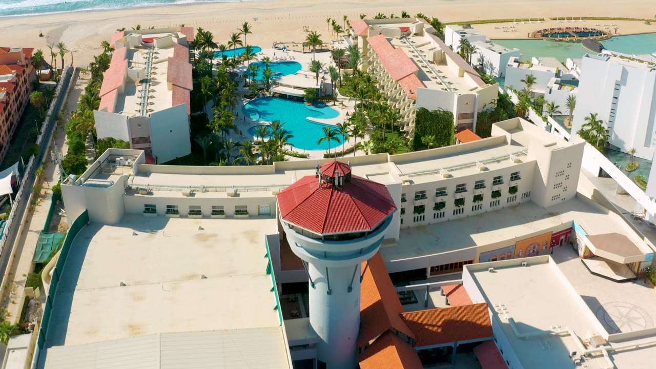 Aerial resort view with pools, palms, beach, and ocean.