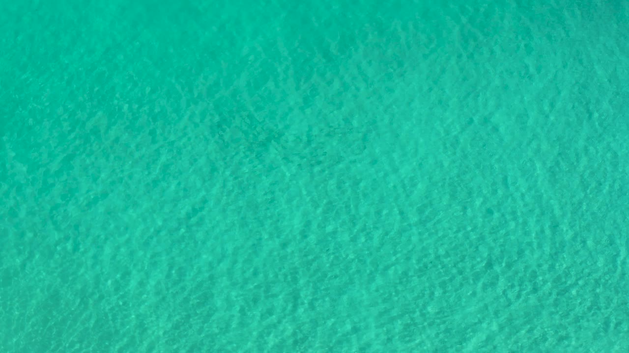 Aquamarine shallow water with subtle darker patches.