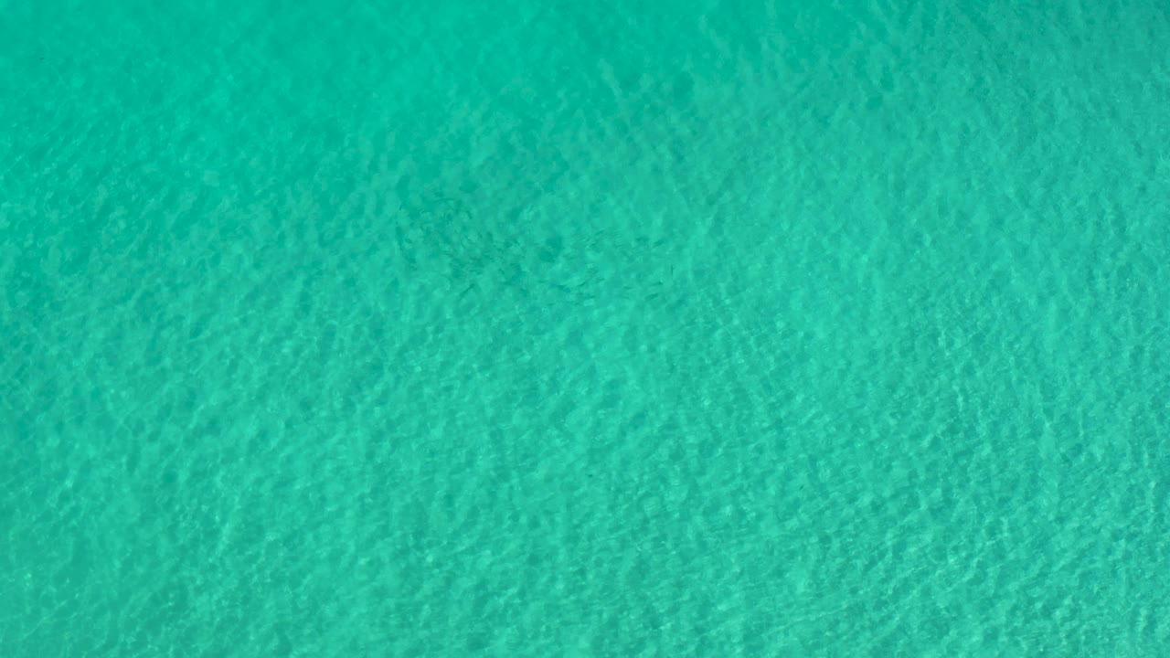 Overhead turquoise shallows in Los Cabos, Mexico, showing fine wave patterns across the frame and no visible people.