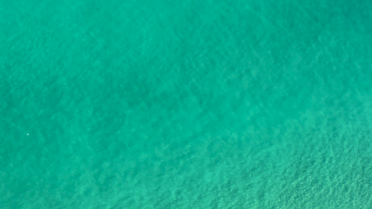 Turquoise-green ocean water fills the frame in Los Cabos, Mexico, with faint ripple texture and no visible people.