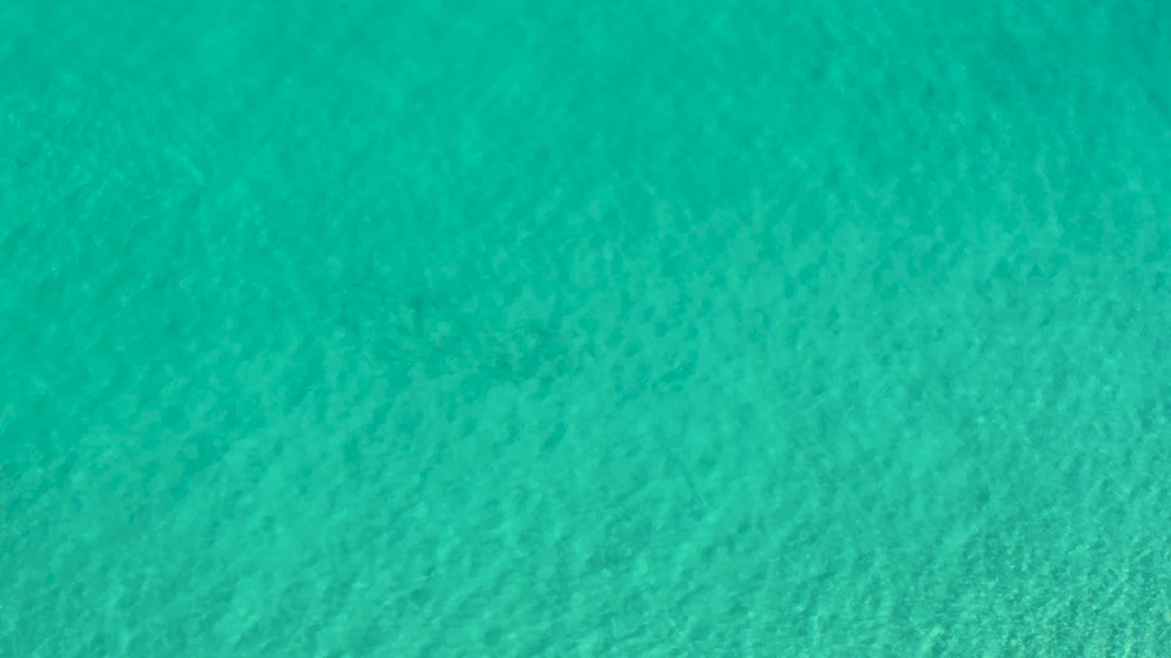 Top-down frame of clear turquoise water in Los Cabos, Mexico, with small wavelets spread evenly across the surface and no visible people.