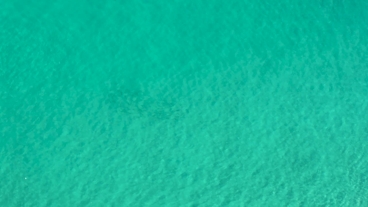 Overhead view of open Los Cabos water with slightly darker teal ripples and no shoreline, boats, or visible people.