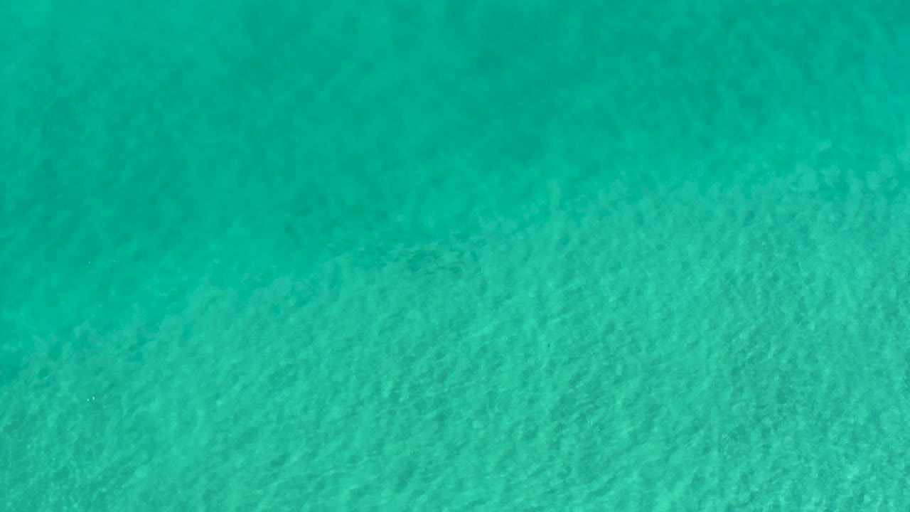 Turquoise Los Cabos water shows shallow-looking surface texture and light ripple bands, with no visible people.