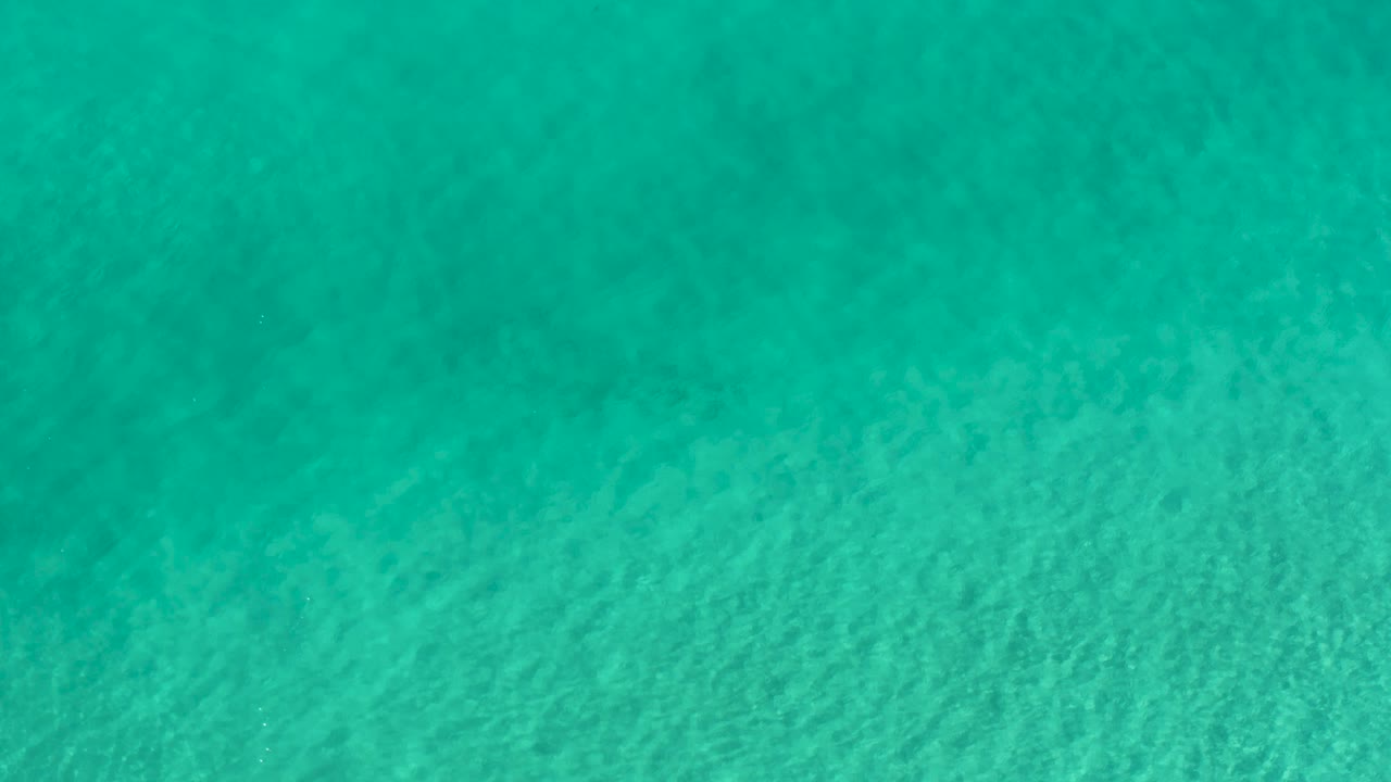 Plain blue-green water in Los Cabos fills the shot with faint wave texture and no visible shoreline or people.