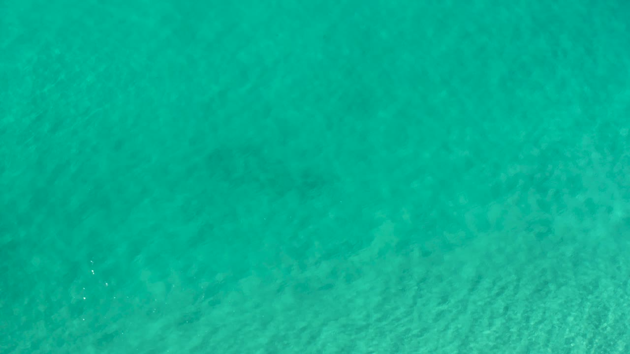 Aqua ocean water from Los Cabos fills the frame with soft ripples and no visible people, boats, or structures.