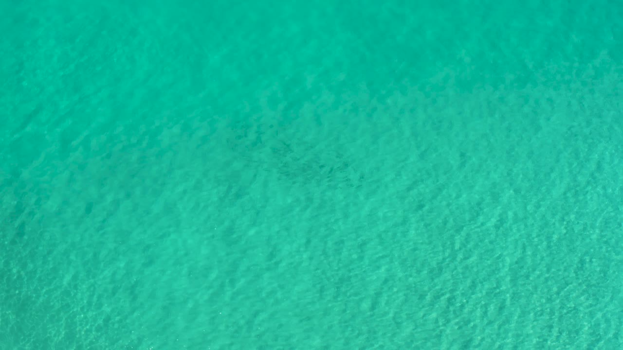 Overhead pool water in Los Cabos, Mexico, with subtle diagonal wave patterns, even blue green color, and no visible people or signage.