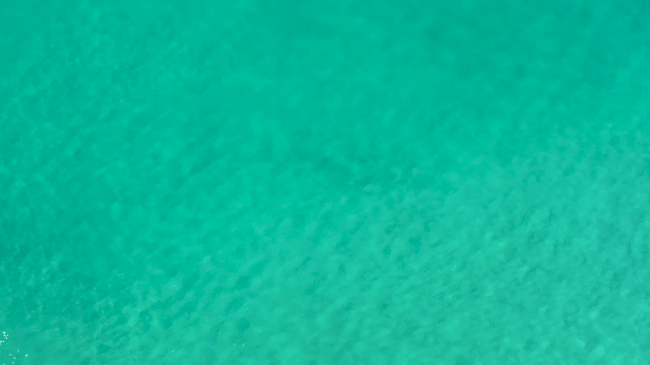 Clear turquoise sea in Los Cabos, Mexico, remains full-frame as brighter ripple patches pass over the visible seabed, with no visible people.