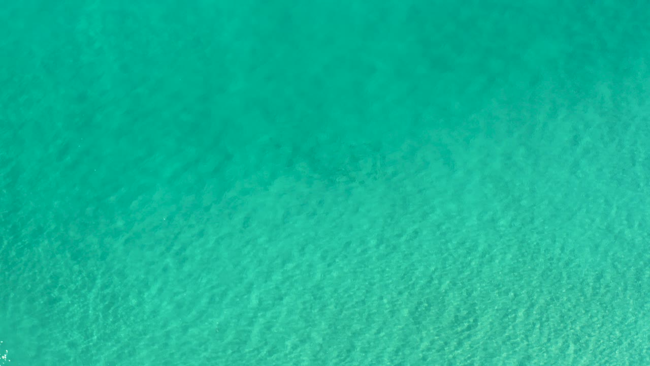Turquoise water with soft ripples seen from above.
