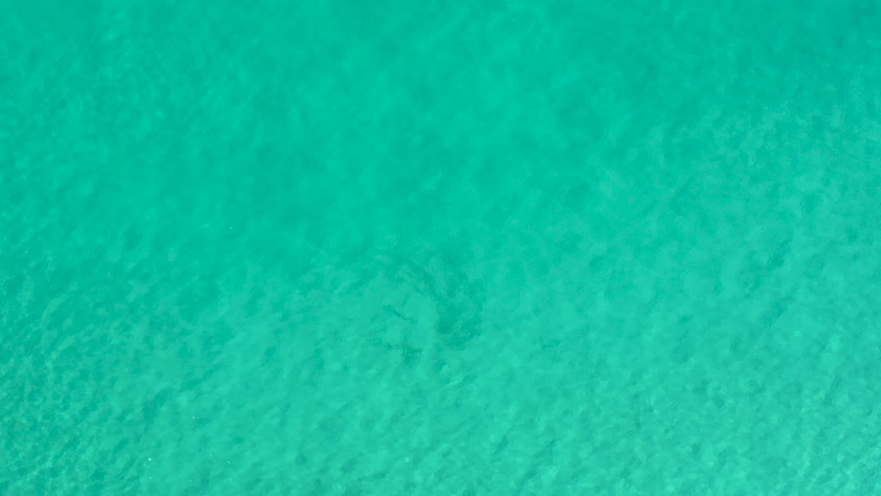 Overhead view of clear turquoise water in Los Cabos, Mexico, with subtle surface ripples and no visible people.