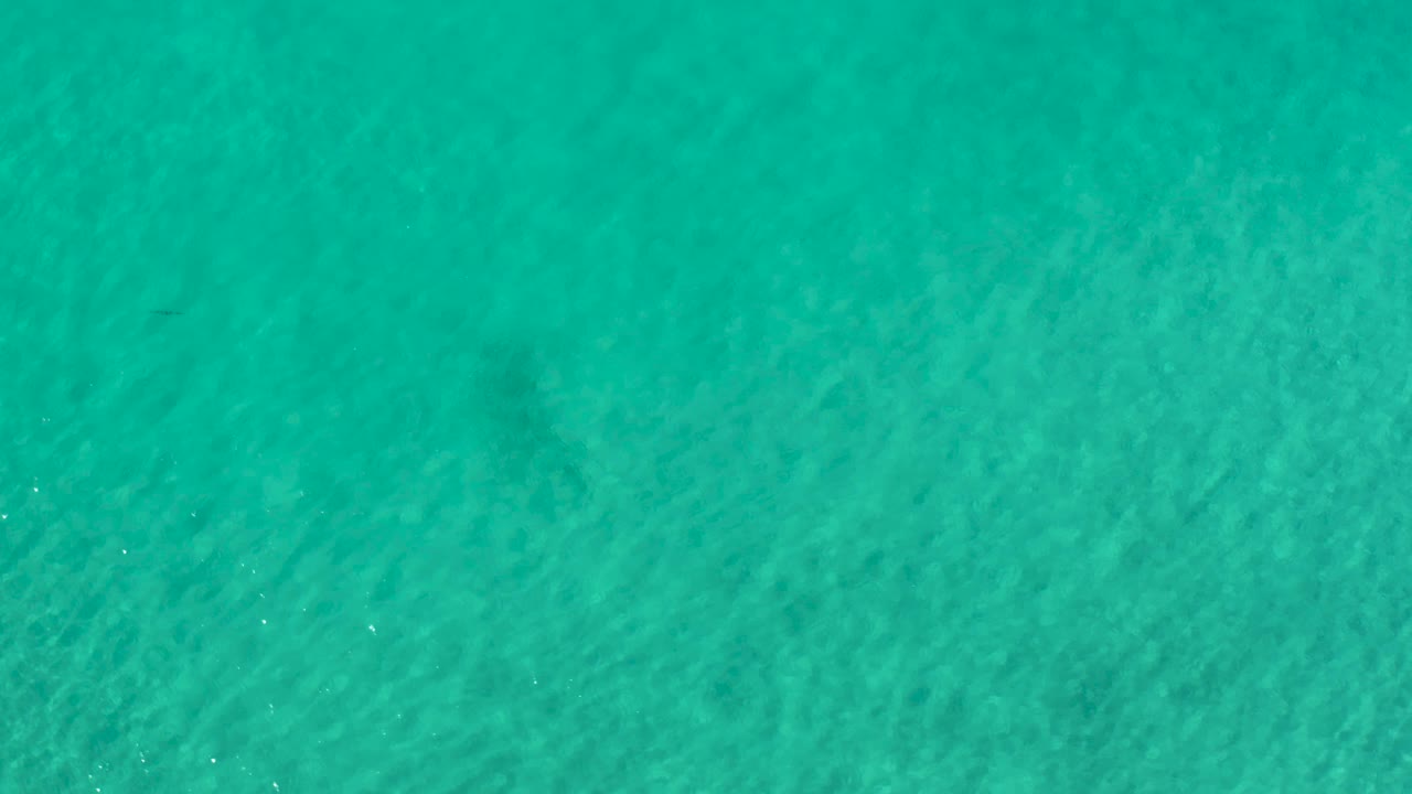 Aquamarine water in Los Cabos, Mexico, shows fine sunlight ripples moving over the pale sandy bottom with no visible people.