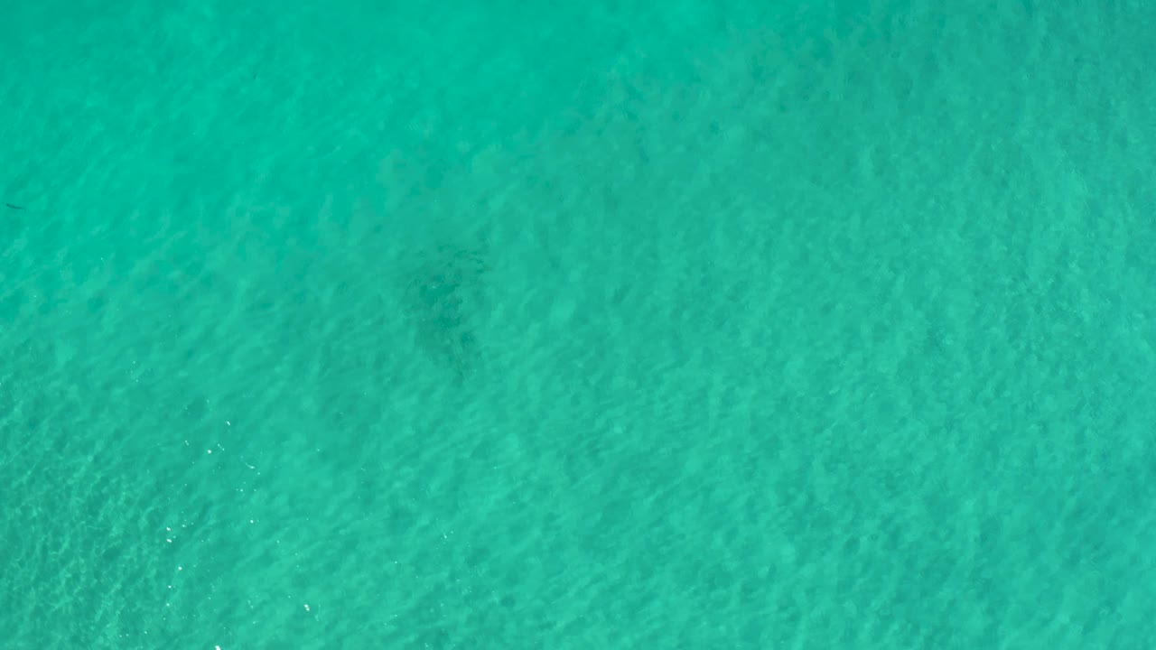 Overhead Los Cabos seawater frame with soft ripple lines, teal color variation, and no visible people.