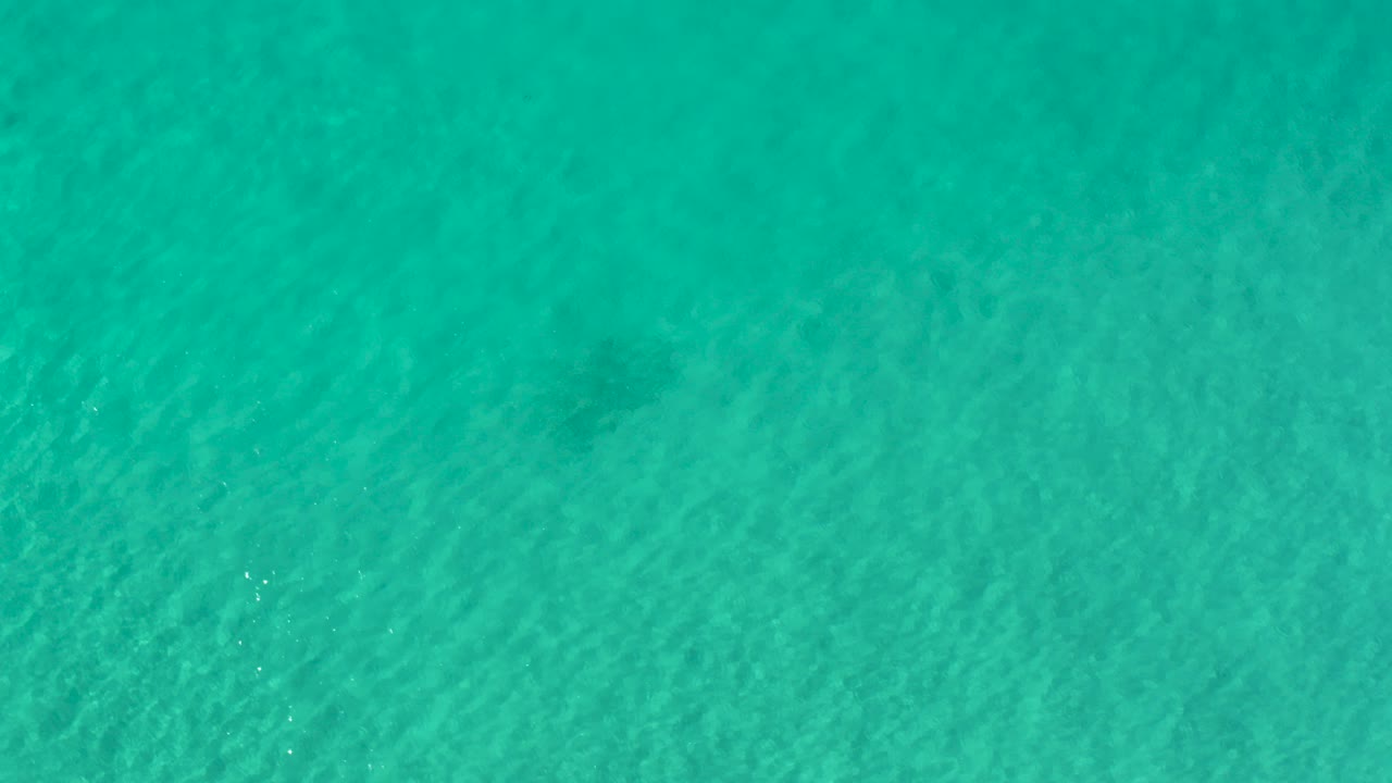 Turquoise ocean water with faint darker patches below the surface.