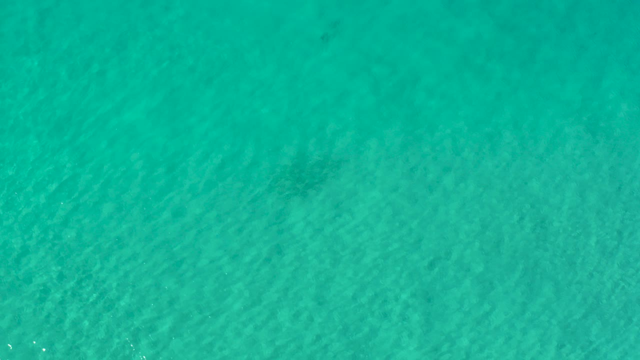 Overhead view of greenish blue ocean water in Los Cabos, Mexico, with fine ripples across the surface and no visible people.
