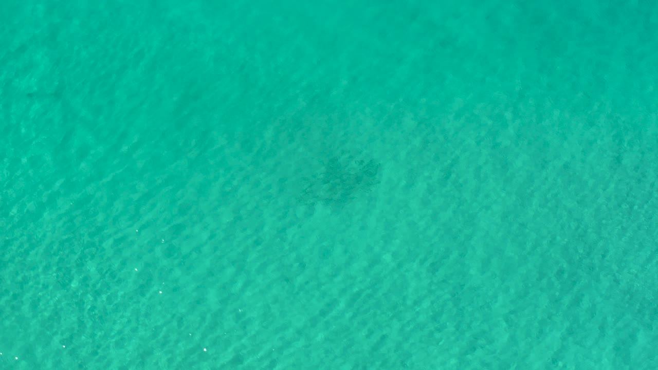 Overhead view of turquoise ocean water in Los Cabos, Mexico, with fine ripples and no visible people.