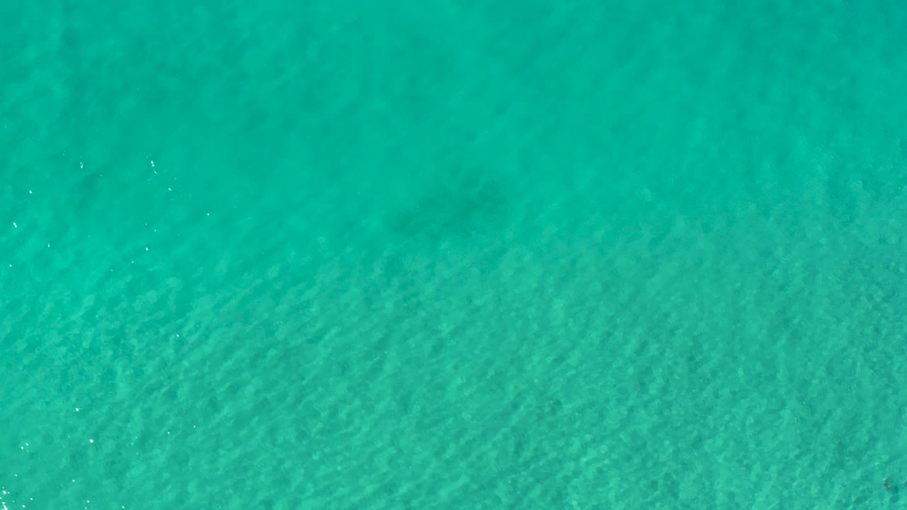 Overhead view of turquoise ocean water in Los Cabos, Mexico, with faint ripples and no visible people.
