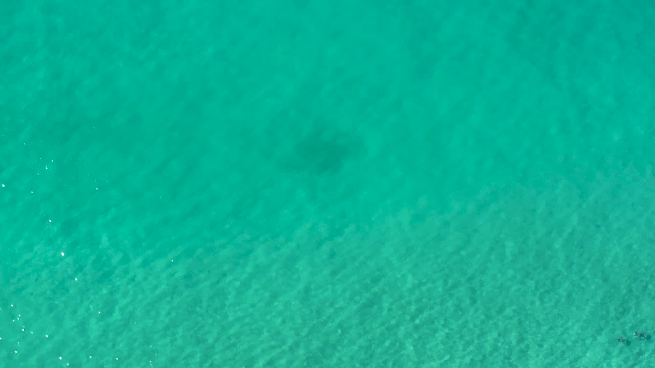 Bright turquoise ocean water in Los Cabos, Mexico, with small sun glints and no visible people.