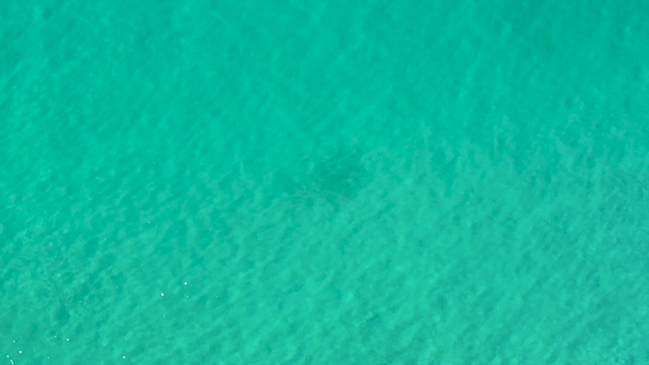 Blue-green ocean water fills the frame in Los Cabos, Mexico, with subtle ripple lines and a slightly darker band near the lower edge, no visible people.