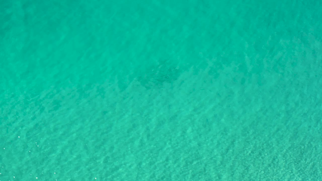 Clear teal shallow water fills the frame in Los Cabos, Mexico, with subtle ripple bands and no shoreline or visible people.