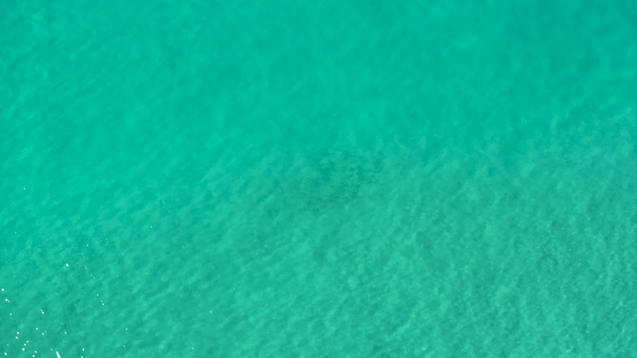 Straight-down view of turquoise water in Los Cabos, Mexico, with soft seabed texture and no visible people.
