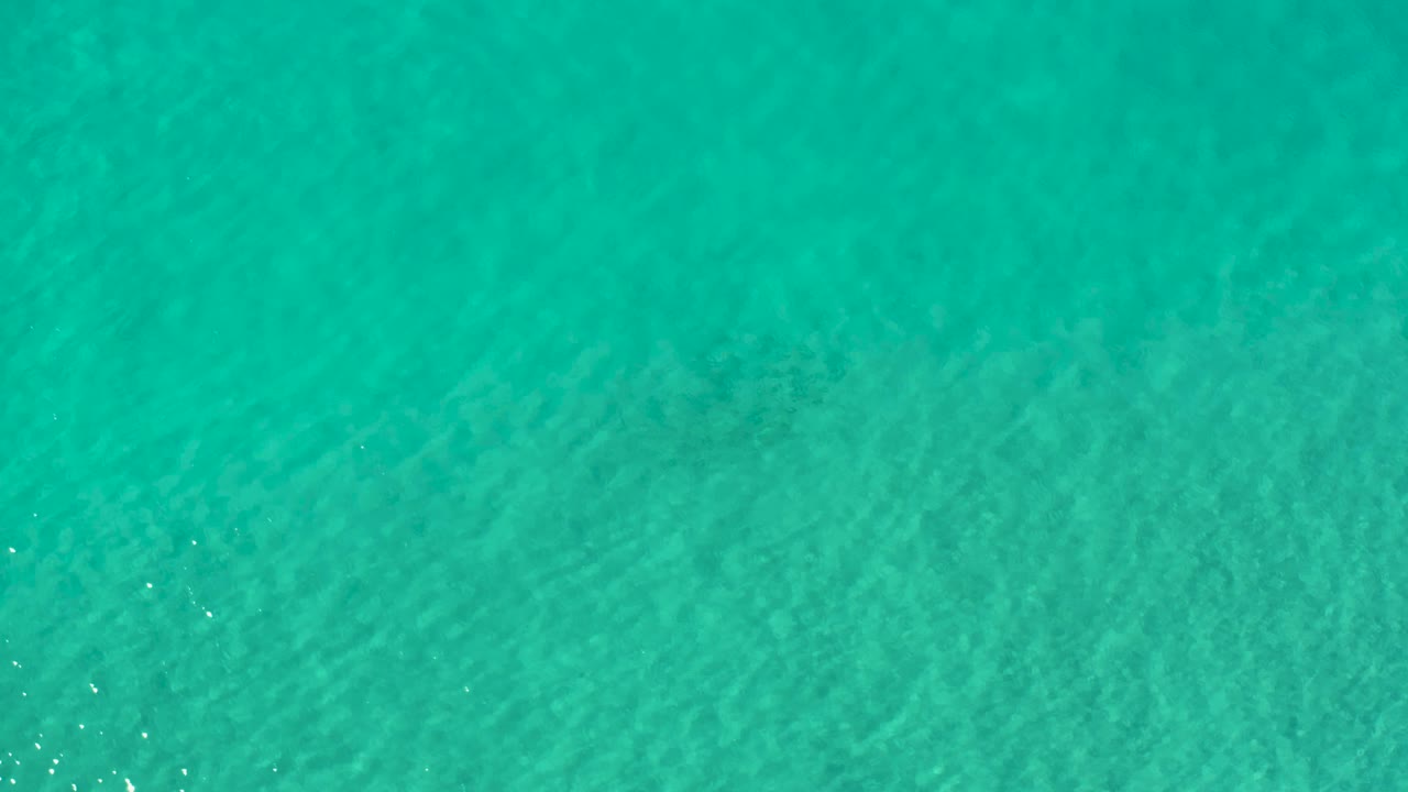 Overhead Los Cabos water surface with a slightly darker turquoise field and no visible people or vessels.