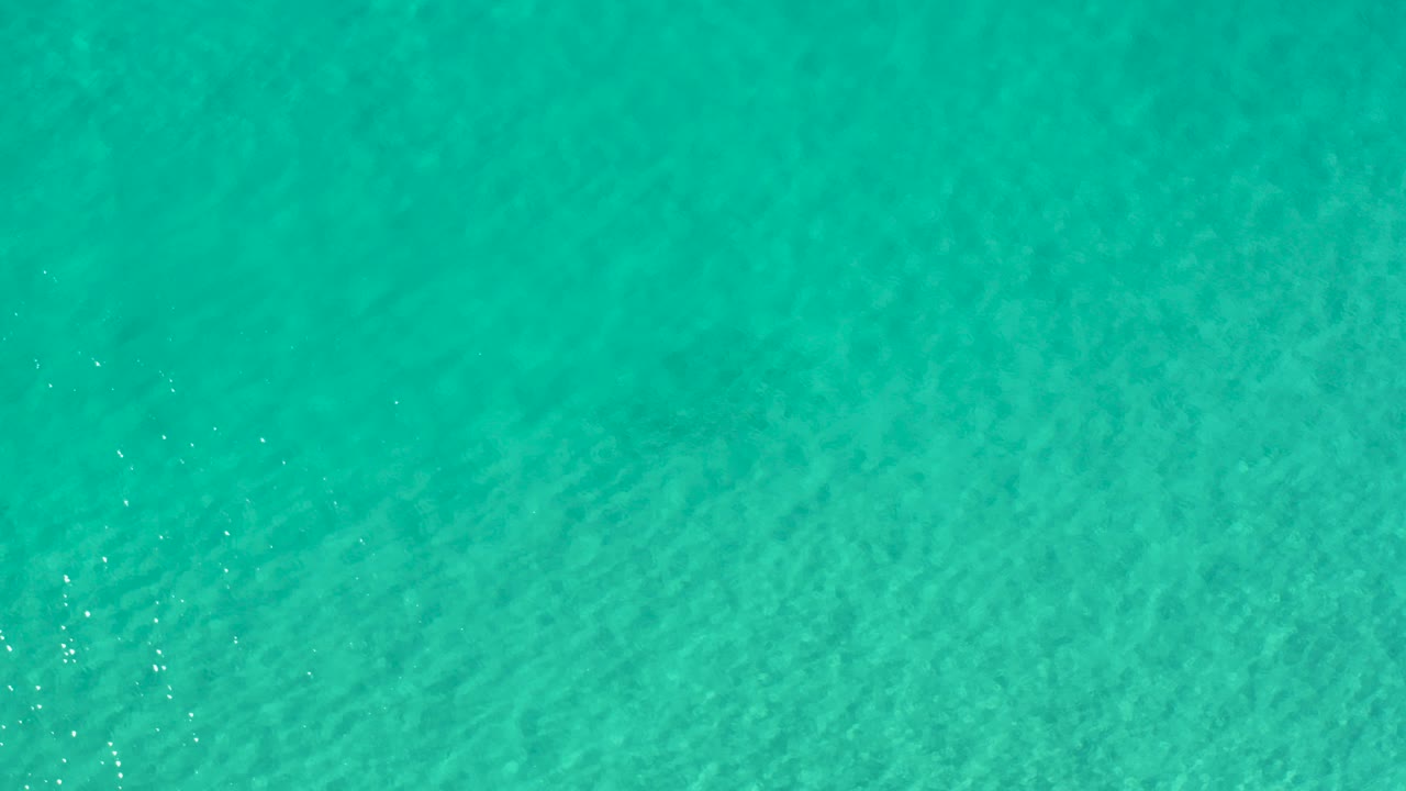 Overhead view of blue-green ocean water in Los Cabos, Mexico, with faint surface texture and no visible people.