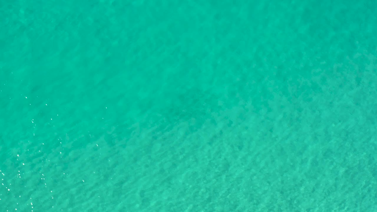 Turquoise ocean surface in Los Cabos, Mexico, seen from above with gentle wave lines and no visible people.