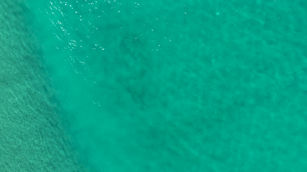 Turquoise water with faint ripples and darker underwater patches.