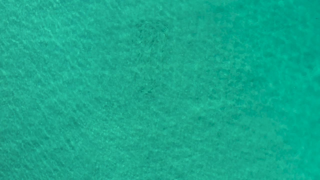 Clear teal ocean water fills the frame in Los Cabos, Mexico, with a slightly brighter lower area, fine wave texture, and no visible people.