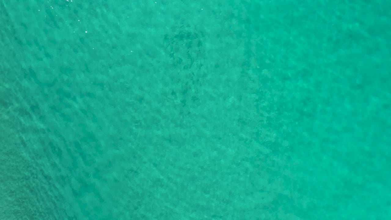 Clear blue-green water fills the frame in Los Cabos, Mexico, with light surface texture and no visible people.