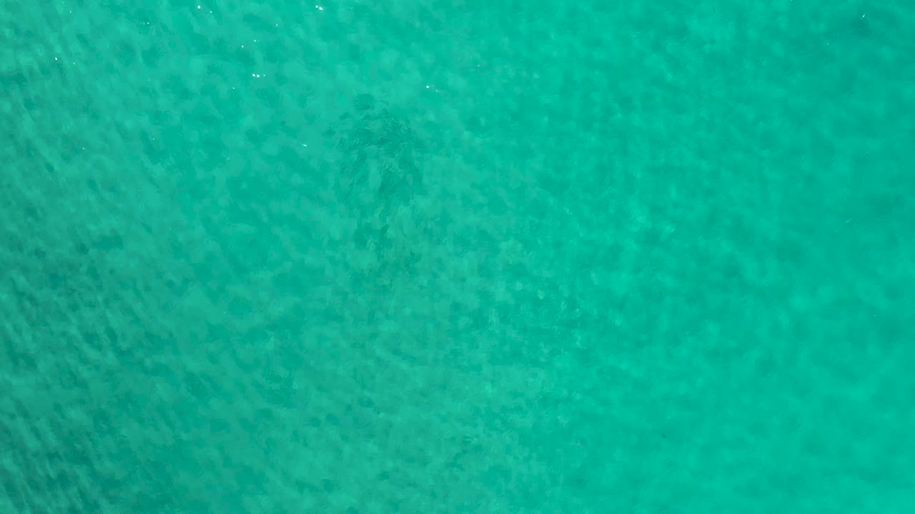 Overhead Los Cabos sea water fills the frame, with a slightly darker diagonal ripple band and no visible people or shoreline.