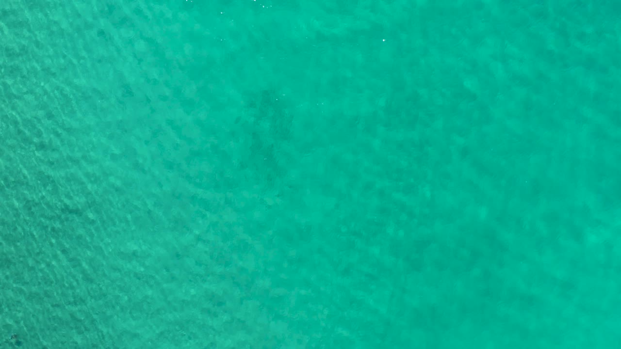 Blue-green Los Cabos water fills the frame, with darker patches visible through the clear surface and no shoreline, vessels, or people.