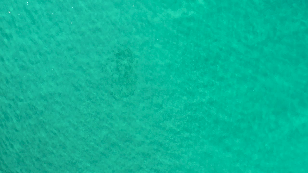 Opening frame of turquoise ocean water seen from above in Los Cabos, Mexico, with faint surface ripples and no visible people.