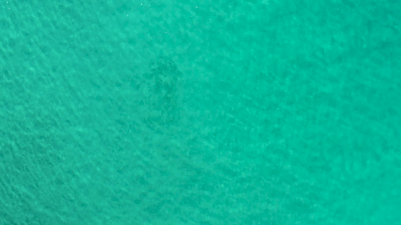 At 0:02, the Los Cabos water appears green-blue from an overhead angle, with mild tonal variation and no boats, land, or visible people.