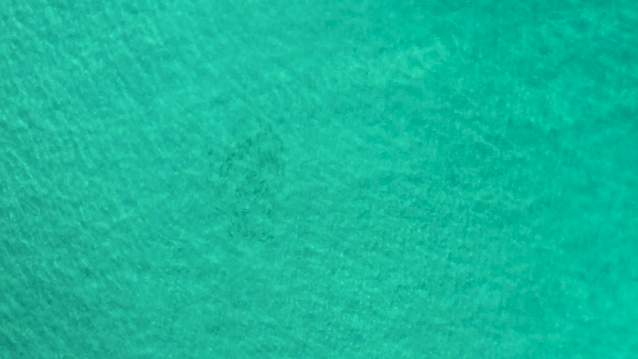 Turquoise ocean surface in Los Cabos, Mexico, showing faint underwater shadows and no visible people.