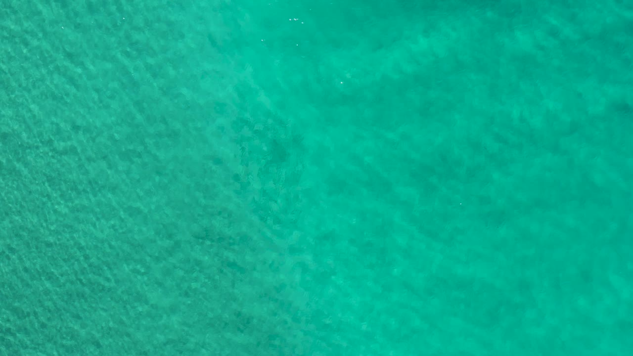 Top-down turquoise sea surface in Los Cabos, Mexico, with small ripple highlights spread across the frame and no visible people.