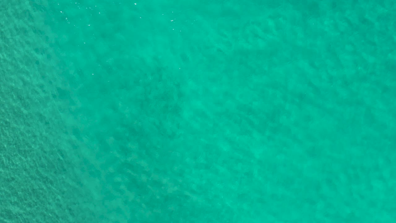 Straight-down view of Los Cabos ocean water with darker green bands under the surface, light ripple movement, and no visible people.