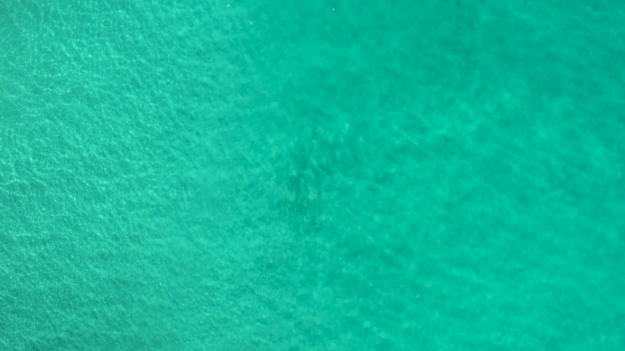 Overhead view of turquoise green water in Los Cabos, Mexico, with fine surface ripples and no visible people.