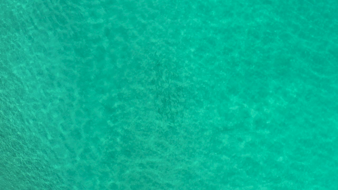 Overhead view of turquoise water in Los Cabos, Mexico, with fine ripples and mottled underwater texture, no visible people.