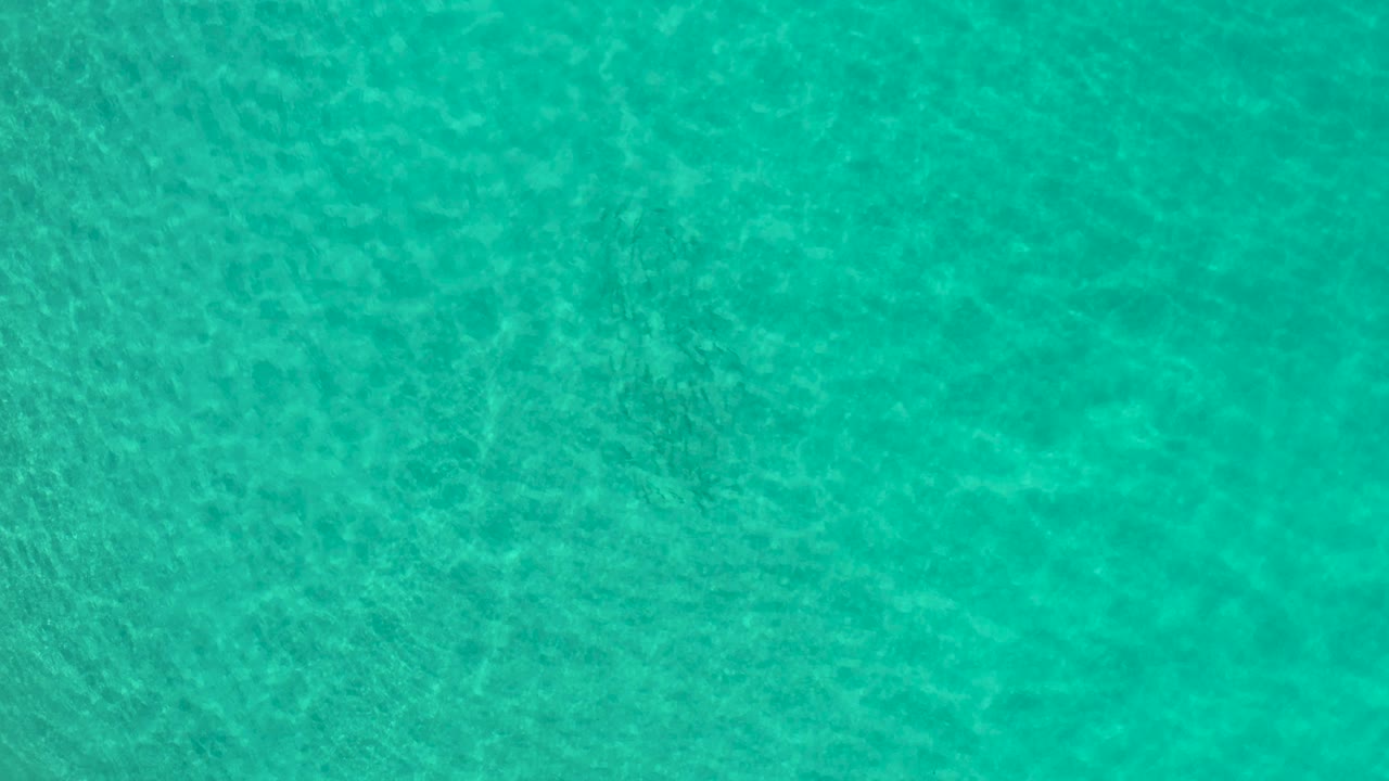 Aerial view of shallow turquoise sea with mottled bottom