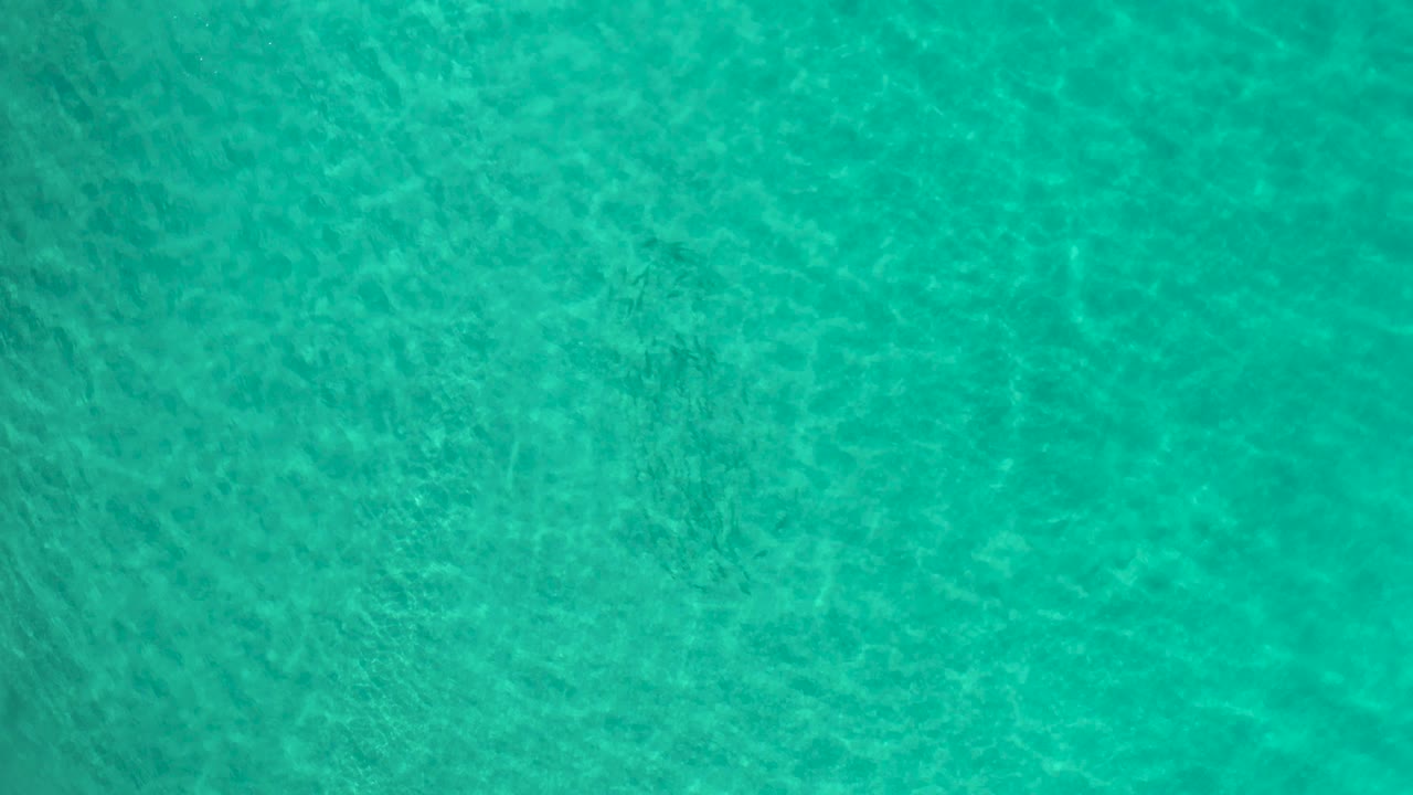 Turquoise water surface in Los Cabos, Mexico, filling the frame with fine wave texture and no visible people, boats, or land.