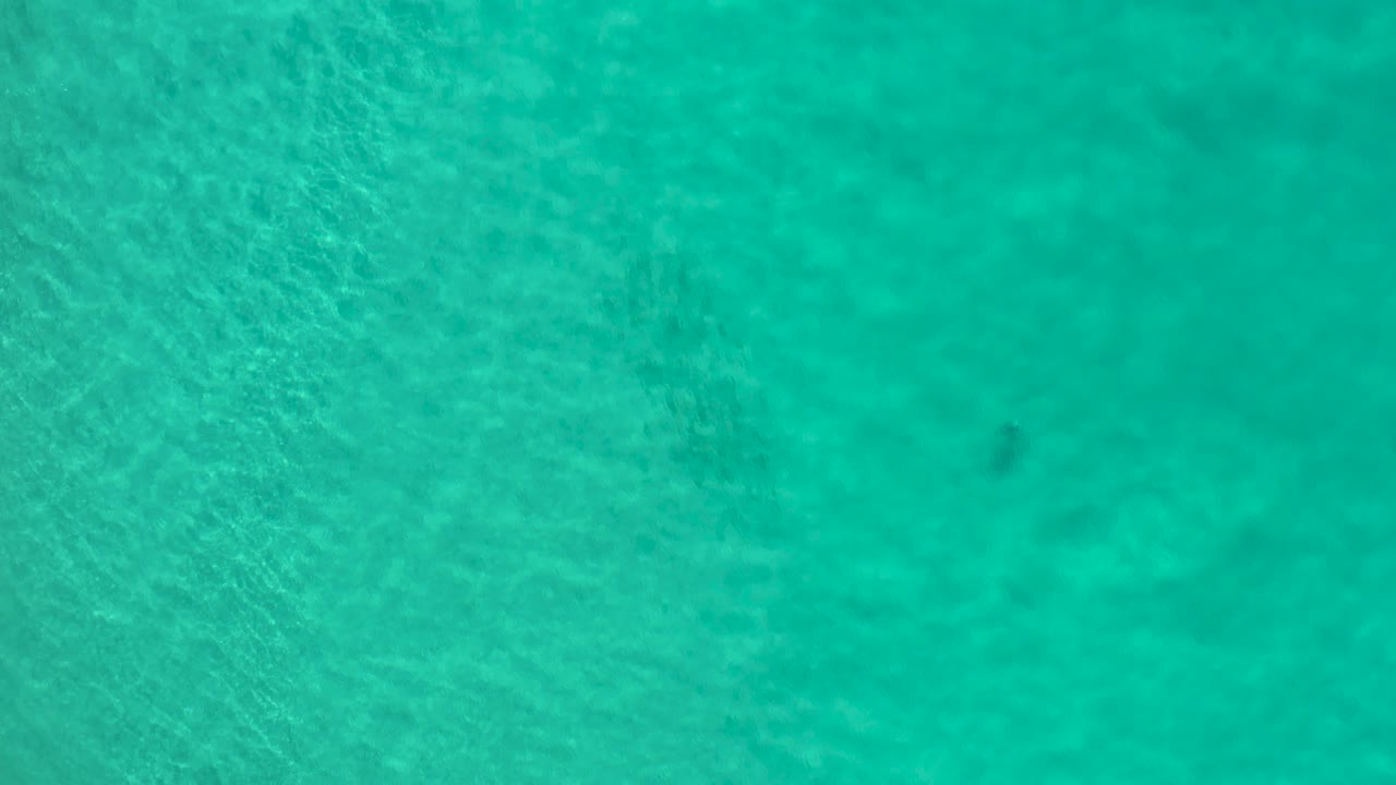 Turquoise Los Cabos ocean water fills the frame with a smoother center area and faint underwater texture, no visible people.