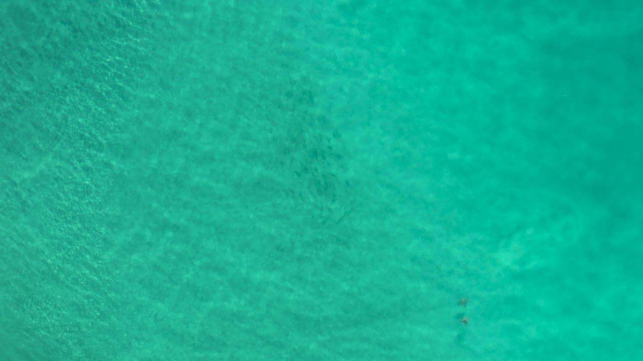 Top-down view of turquoise shallow ocean water.