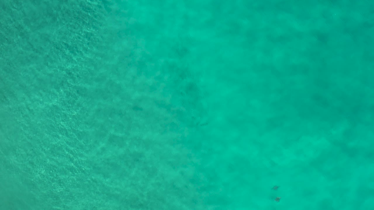 Aerial Los Cabos ocean view with the frame filled by calm turquoise water, gentle tonal variation, faint ripples, and no visible people.
