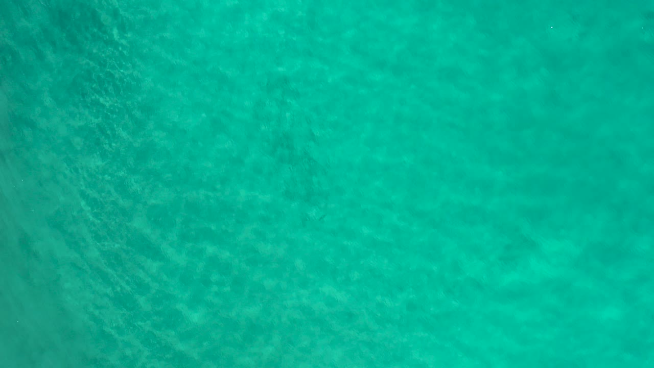 Overhead view of turquoise open water in Los Cabos, Mexico, with fine ripples and no visible people.