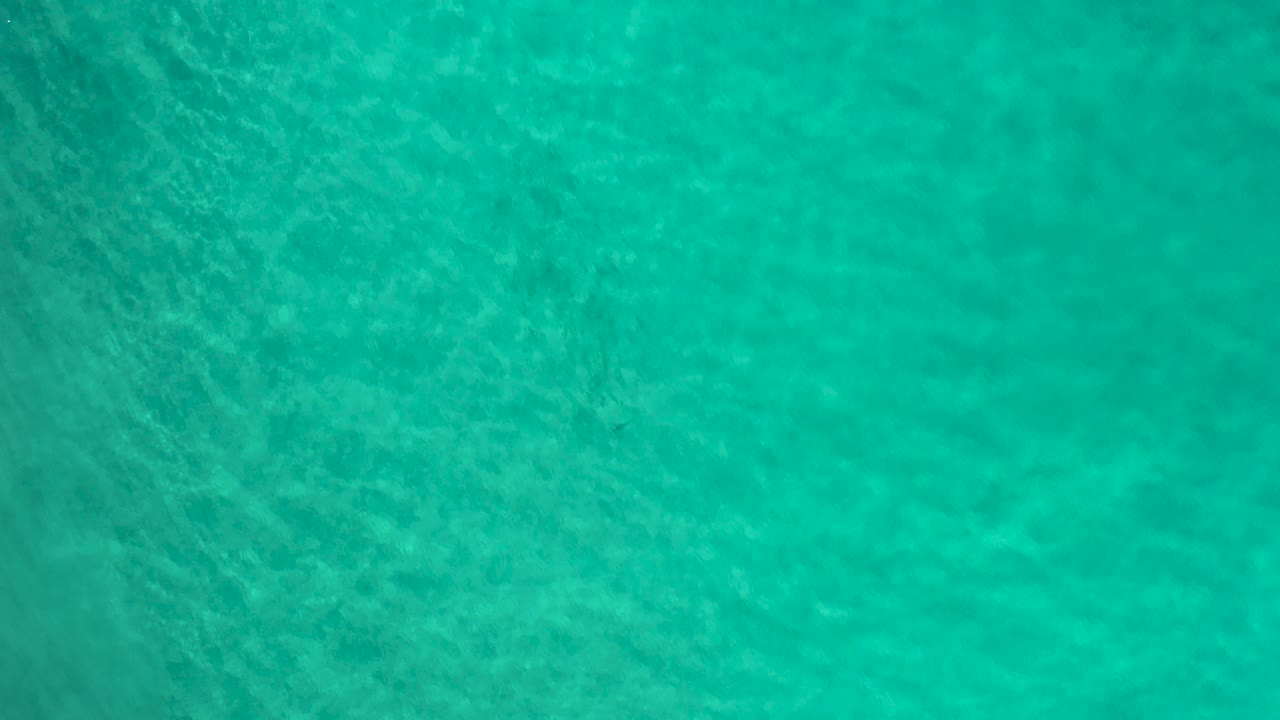 Turquoise sea in Los Cabos, Mexico, seen from above with diagonal ripple patterns and no visible people or boats.
